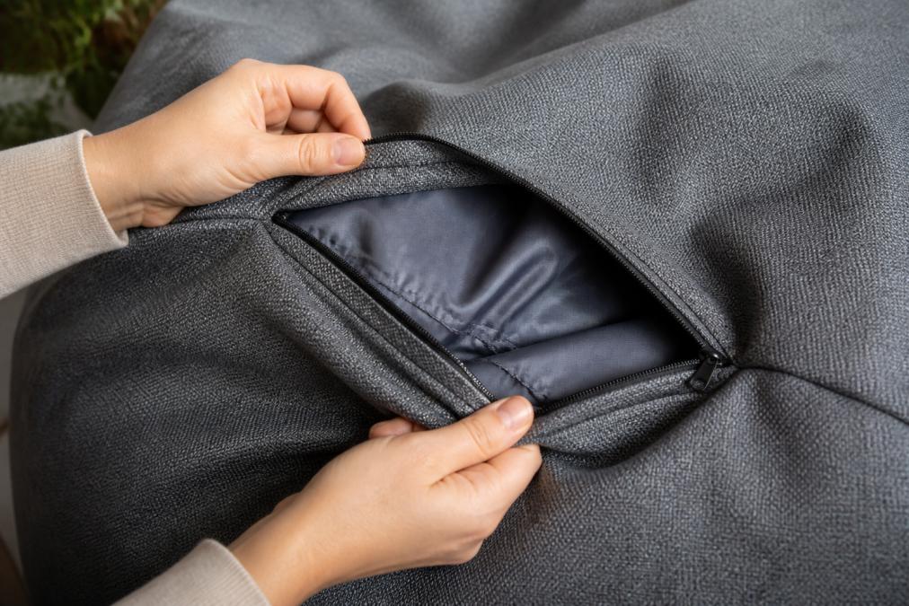 Close-up of high-quality beanbag fabric texture showing removable cover with visible anti-abrasion stitching detail, hands gently handling the material to show durability