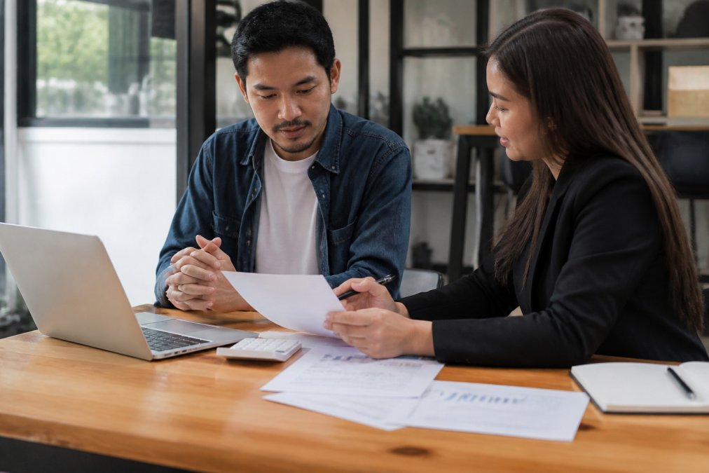 Small business owner reviewing financial reports and discussing cash flow with an accountant at a desk with laptop and papers