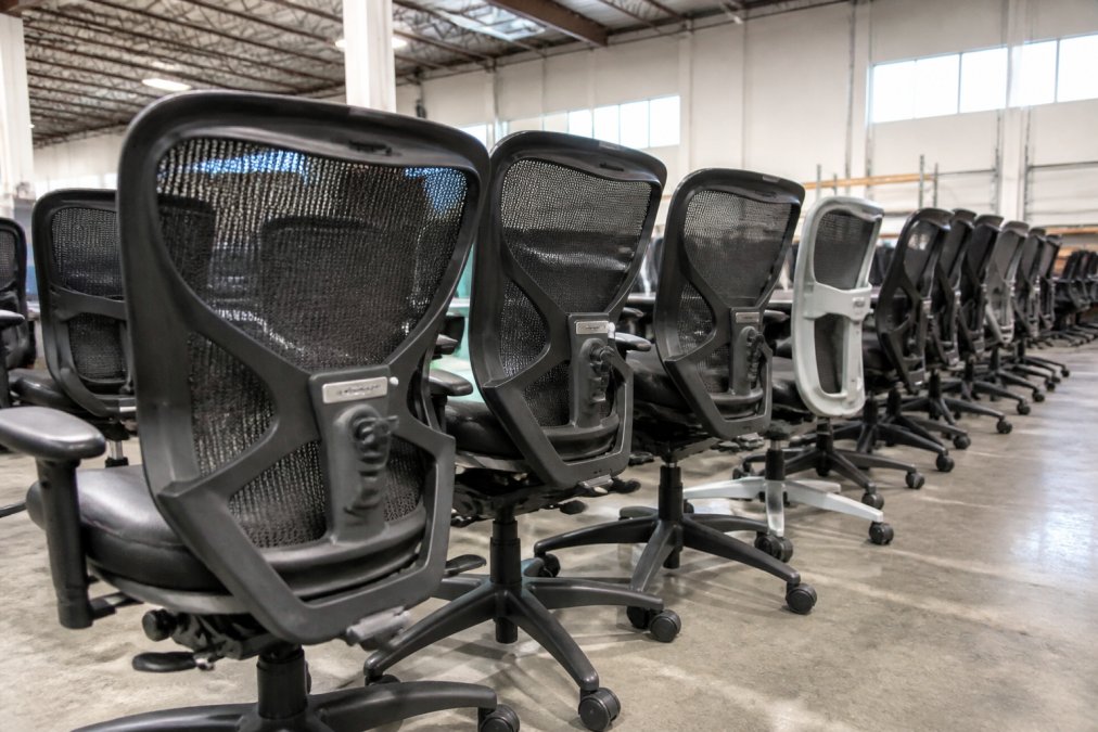 A row of pre-owned office furniture featuring Steelcase ergonomic chairs displayed in a bright warehouse showroom