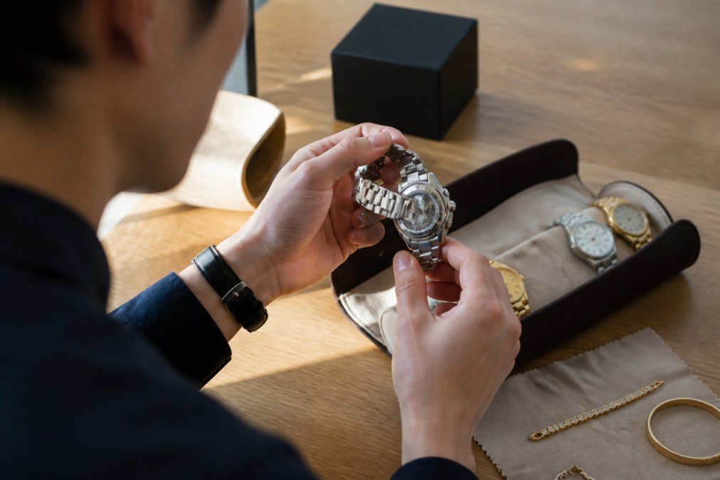 Close-up of hands examining product details, reading authenticity labels, checking condition on pre-loved luxury item with natural lighting