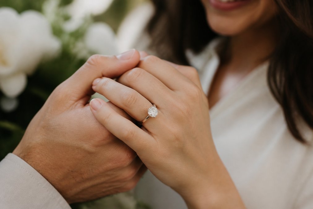 Couple holding hands with a sparkling lab-grown diamond ring, a top choice for sustainable engagement rings.