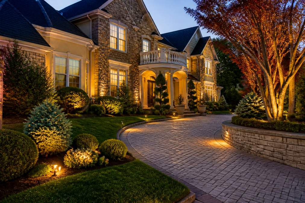 Luxury residential home at dusk featuring consolidated landscaping services with defined hardscaping and lighting.