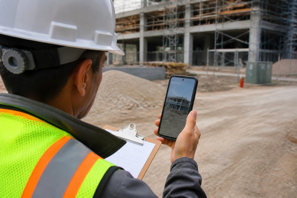 Inspector using a smartphone to capture data for geotagged inspection reports at a building construction site