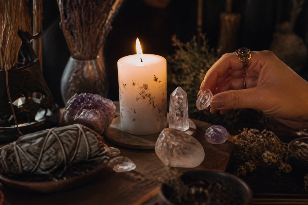 A sacred space altar with a lit intention candle, crystals arranged intentionally, and spiritual items creating a serene, meditative environment with soft candlelight