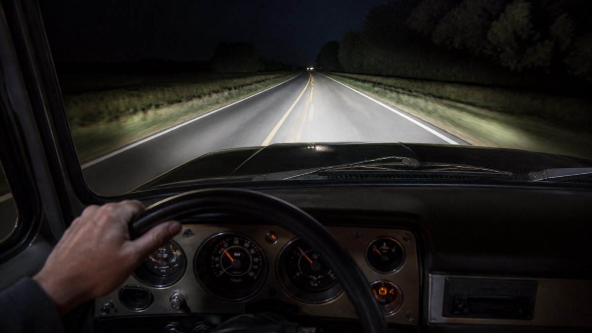 Bright white LED headlights illuminate a dark road from a driver's perspective at night.
