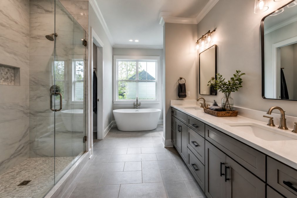 A bright, newly renovated master bathroom in a Dallas home featuring a double vanity, walk-in shower with glass doors, and modern tile flooring, with natural light streaming through a window