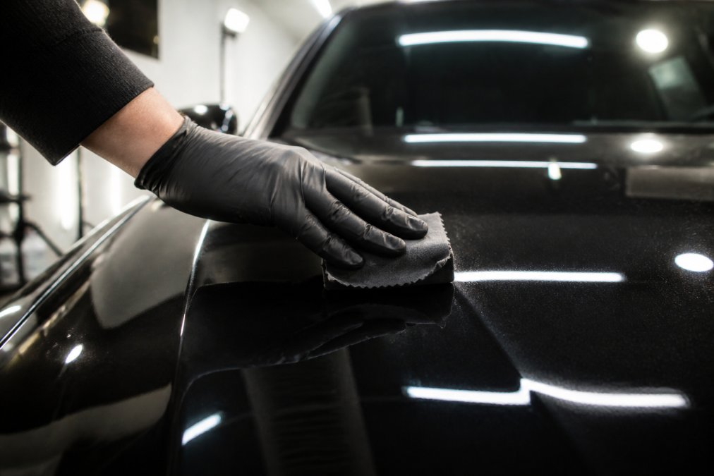 Detailer applying professional ceramic coating to a black car hood