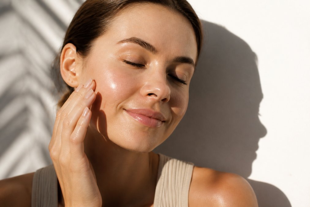 Close-up of a woman's glowing, smooth facial skin in natural morning light, emphasizing texture and radiance