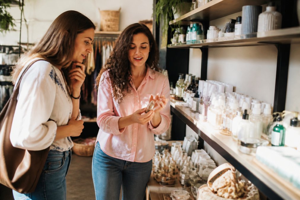 Boutique stylist helping customer select from carefully organized display of beauty products and accessories, showing one-on-one attention and personalized guidance in well-lit retail space