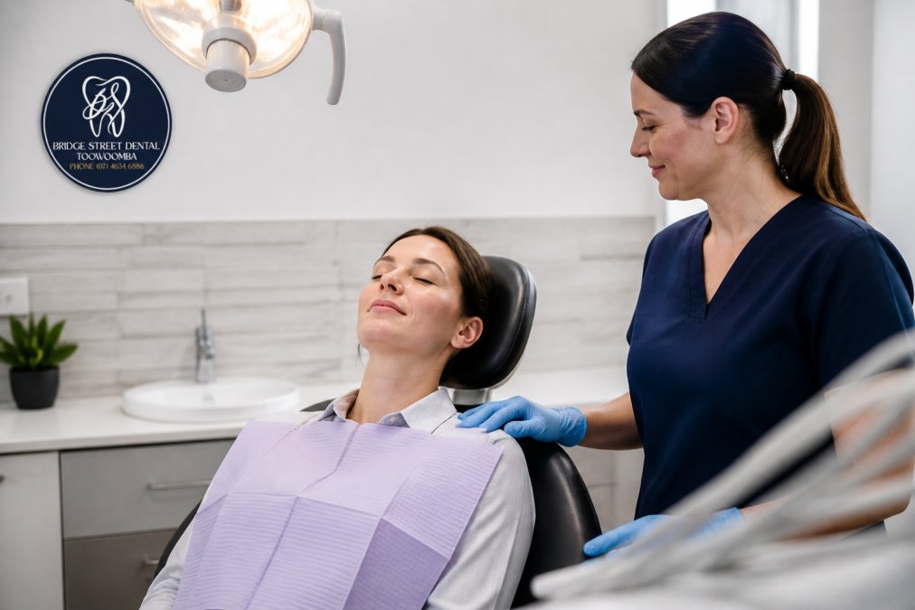 Calm patient reclining in a modern dental chair during sleep dentistry, with a professional offering reassurance.