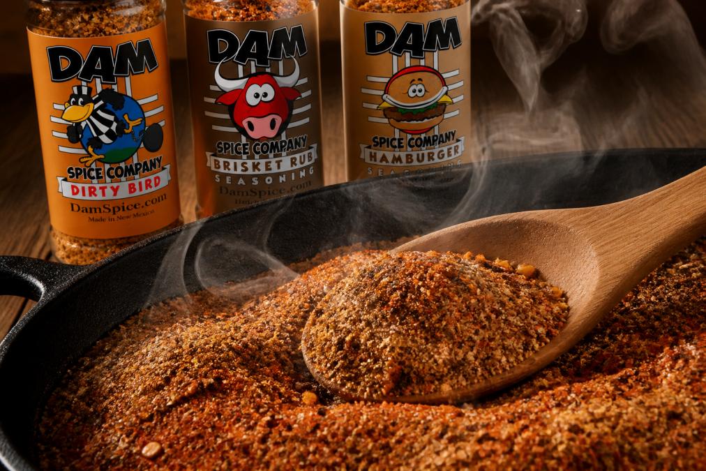 Close-up of freshly ground spice blend with visible aromatic oils and vibrant rust-red and golden hues, wooden spoon resting in the blend with steam rising from the surface