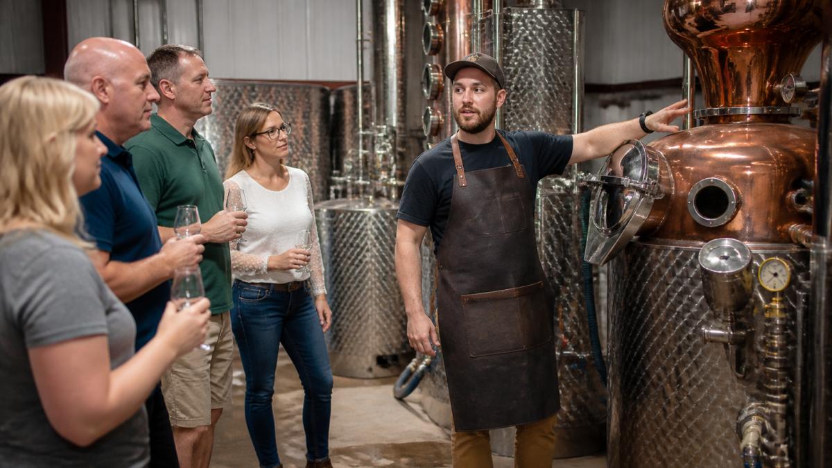 Distiller explaining the copper still to visitors at one of the many family owned distilleries during a tour.