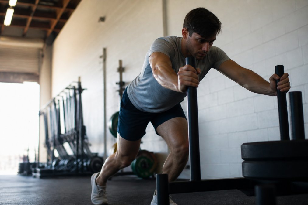 An athlete in a bright gym wearing simple, unbranded athletic apparel, mid-workout with a focused expression, natural lighting, candid documentary style