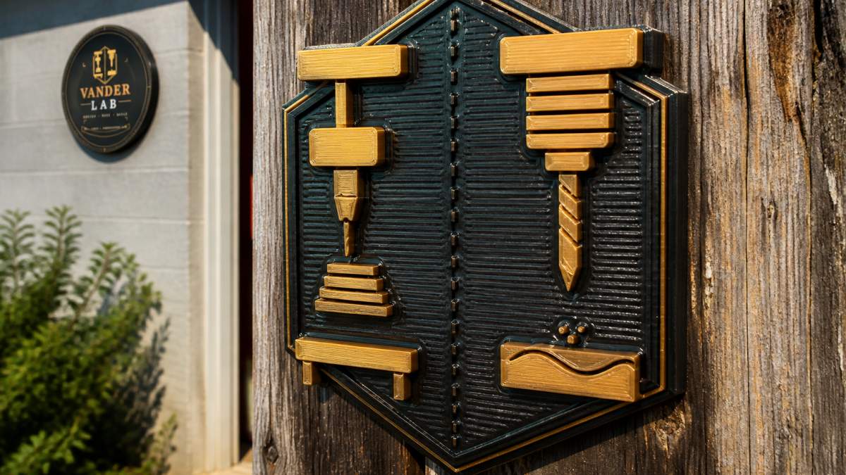Close-up of a finished 3D-printed outdoor sign mounted on a weathered wooden post, showing fine surface detail, rich color saturation, and protective coating sheen under natural daylight