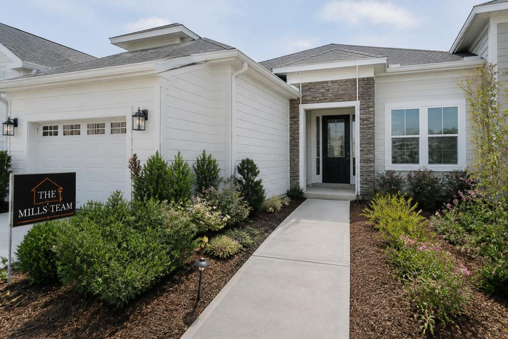 Modern single-story home exterior with low-maintenance landscaping, contemporary architectural design, and accessible entryway typical of new construction 55+ development