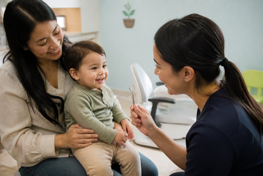 Infographic showing the steps of a child’s first dental exam with a toddler and dentist in a friendly office.