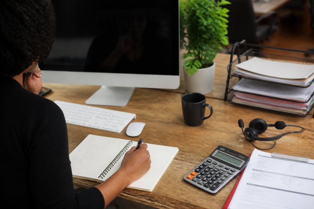 Customer service representative assisting a customer via live chat on a computer screen, with headset on desk and customer notes visible