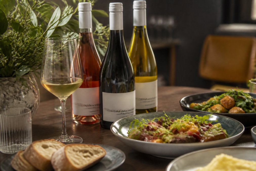 Miris Blend lifestyle image showing premium alcohol-free wine bottles with food pairing