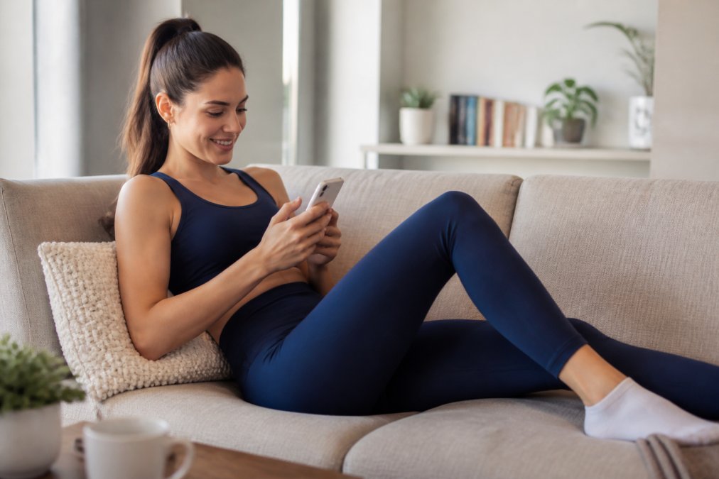 Woman relaxing on a sofa in athleisure, enjoying a quick recovery as one of the best alternatives to surgical liposuction.