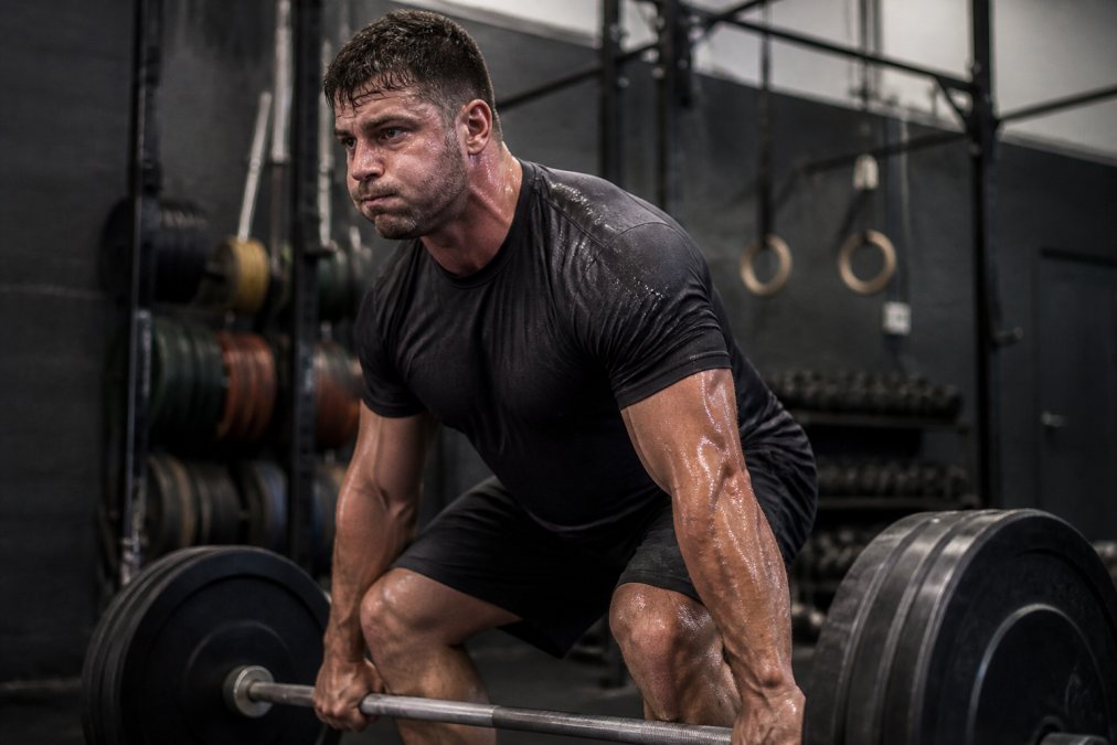 Athlete wearing black athletic apparel performing a heavy barbell lift in a gym