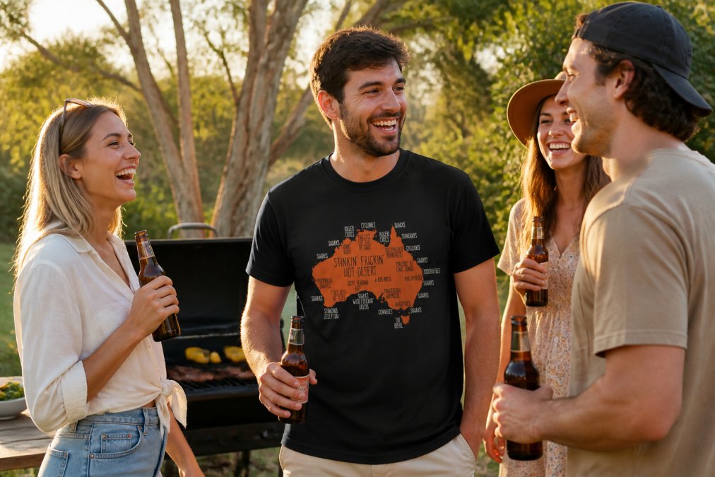 A group of friends laughing together outdoors at a backyard barbecue, one person wearing a black novelty Australian-themed graphic t-shirt, warm afternoon sunlight filtering through eucalyptus trees