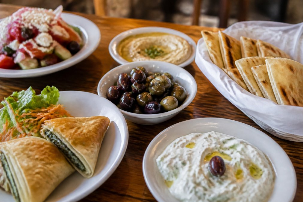 Infographic showcasing traditional mezze items for authentic Greek food, including tzatziki, olives, and pita.
