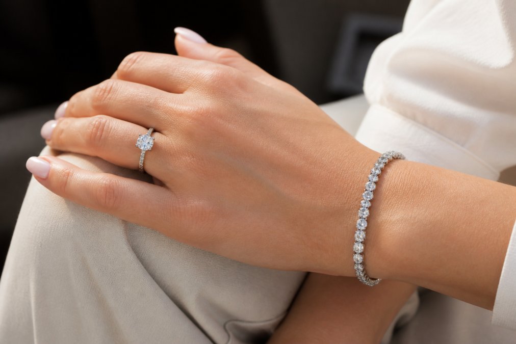 Close-up of a woman's hand wearing an elegant diamond ring and bracelet, natural light highlighting the gemstones and precious metal craftsmanship
