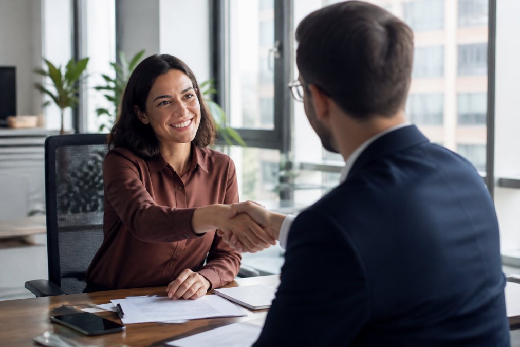 Business owner and consultant shaking hands in a modern office setting after successful initial consultation meeting, natural window lighting