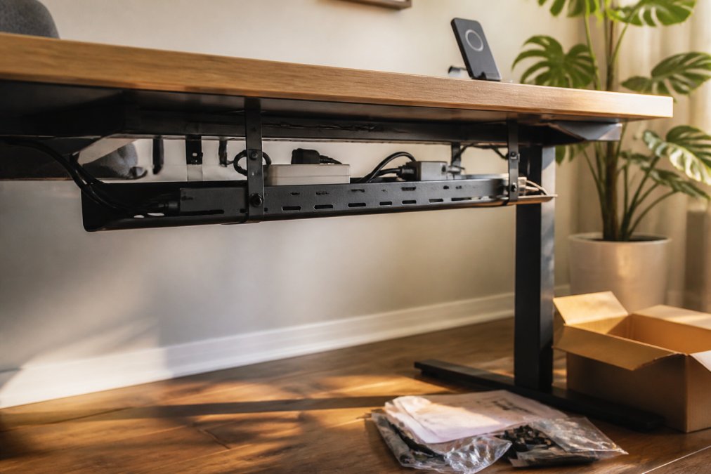 Diagram of an under-desk metal tray organizing power strips and cables as part of effective cable management solutions
