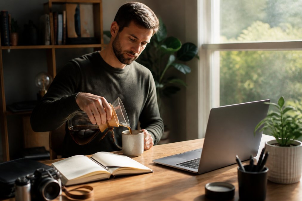 Remote worker pouring the best coffee for intense focus 2026 into a mug in a bright, sunlit home office workspace.