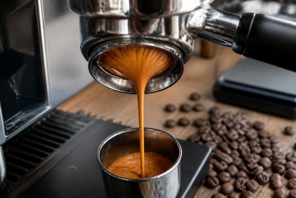 A bottomless portafilter pulling a rich espresso shot with tiger-striped crema on a digital scale