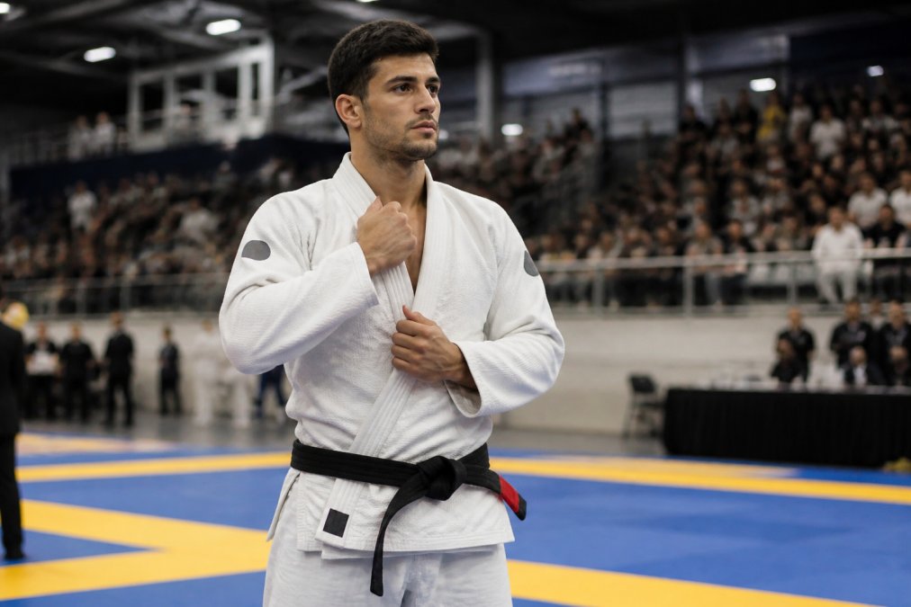 BJJ athlete adjusting their white competition gi before a tournament match with spectators in the background