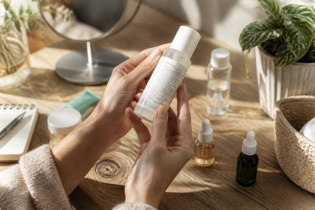 Close-up of hands holding a K-beauty product bottle, examining certification logos and ingredient labels in natural light