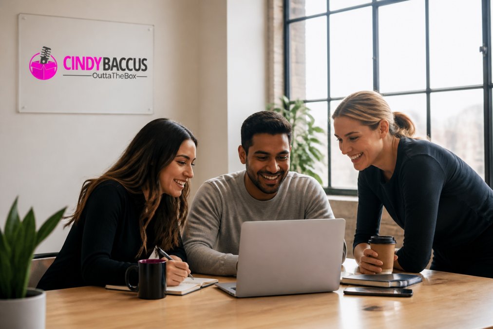 A small marketing team of three people gathered around a laptop reviewing an analytics dashboard, coffee cups and notebooks on the table, casual bright office setting with large windows