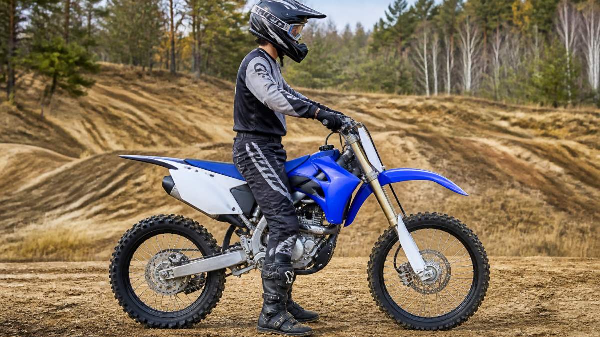 Beginner rider of average height sitting on dirt bike with proper seat height alignment, feet flat on ground, demonstrating correct fit and posture in outdoor terrain