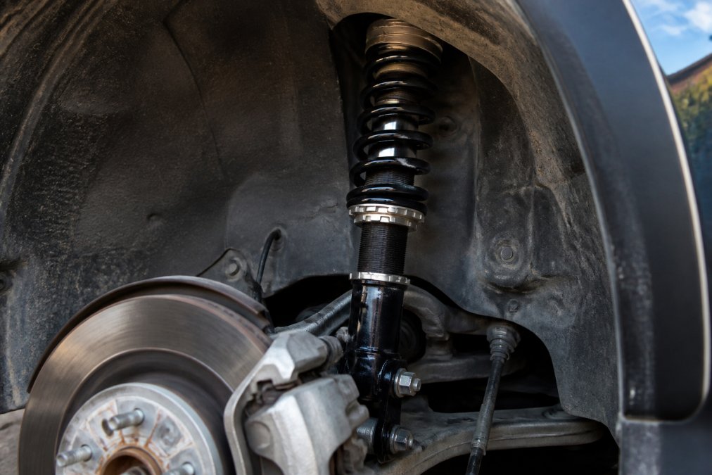 Close-up of a coilover suspension system installed on a vehicle wheel, showing the shock absorber and spring assembly with metal components visible