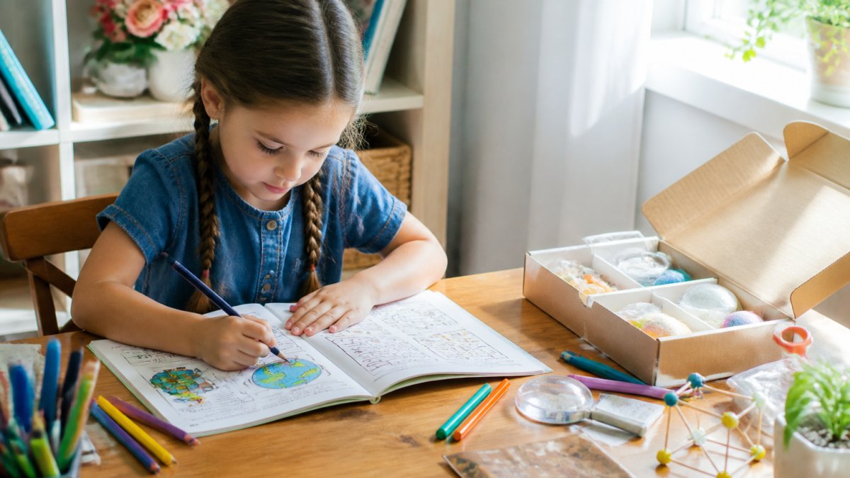 A seven-year-old child sitting at a bright wooden table, focused on coloring and solving puzzles in an activity book, colored pencils and markers spread nearby, natural sunlight streaming through a window