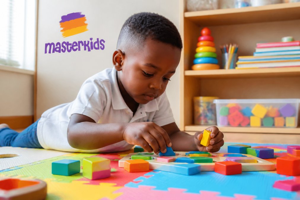 Young child concentrating on a colourful puzzle or building blocks on a bright play mat, hands actively engaged with the toy, natural daylight from nearby window
