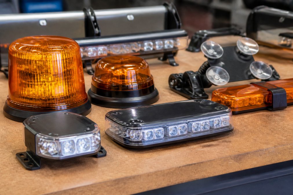 Best Emergency Warning Lights for Cars Close-up of various emergency warning lights and beacons displayed together, showing LED strobe lights with magnetic bases, suction cups, and different mounting options on a workbench
