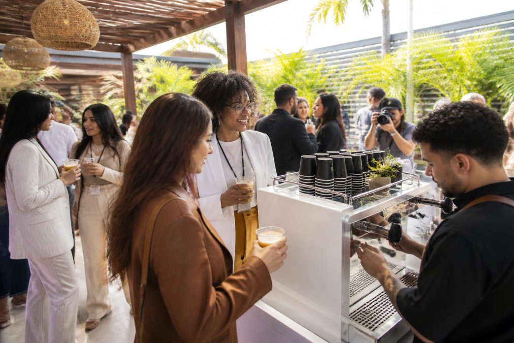 Lively brand activation event with guests gathered around a mobile espresso bar enjoying handcrafted drinks while social media content is being captured in the background