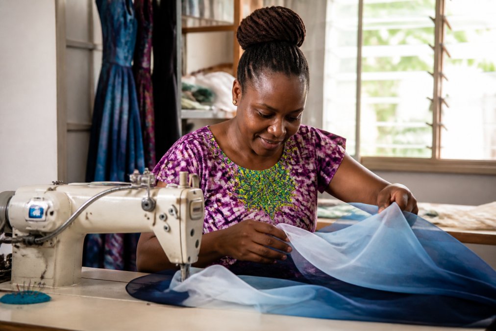 Artisan hands sewing vibrant blue ombré organza for one of the best ethical bridesmaid dress brands in a sunny studio.