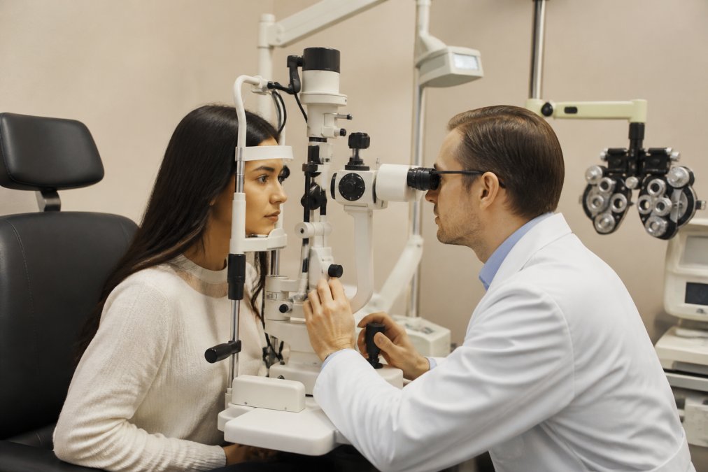 Optometrist performing dilated eye examination on patient using advanced diagnostic equipment in modern clinical setting with professional lighting