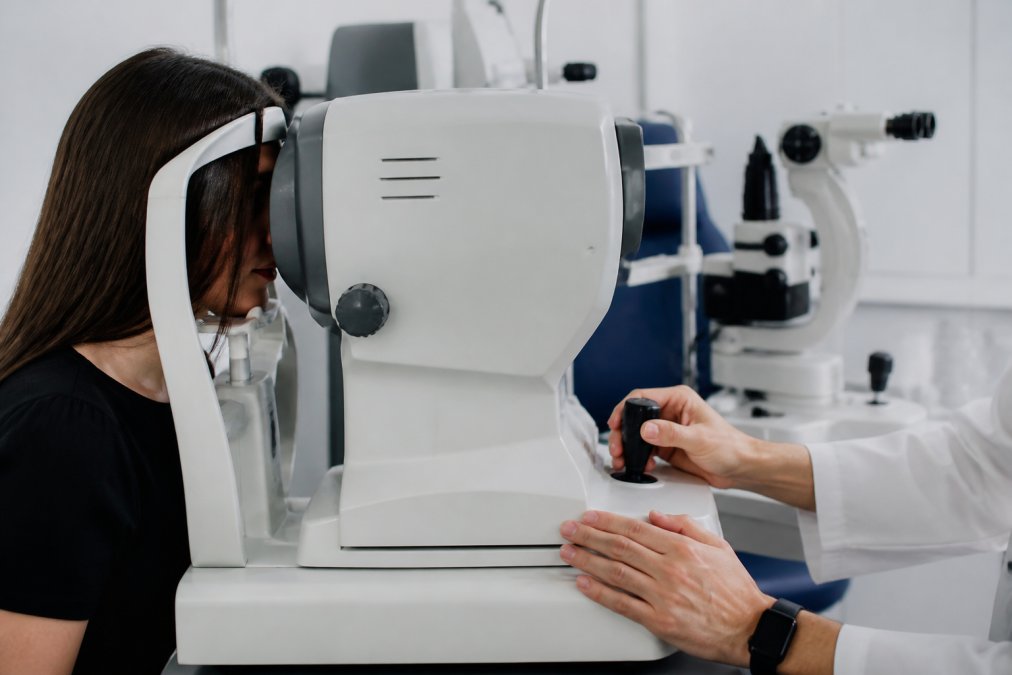 Close-up of advanced eye examination technology including OCT machine in modern clinical setting with soft lighting