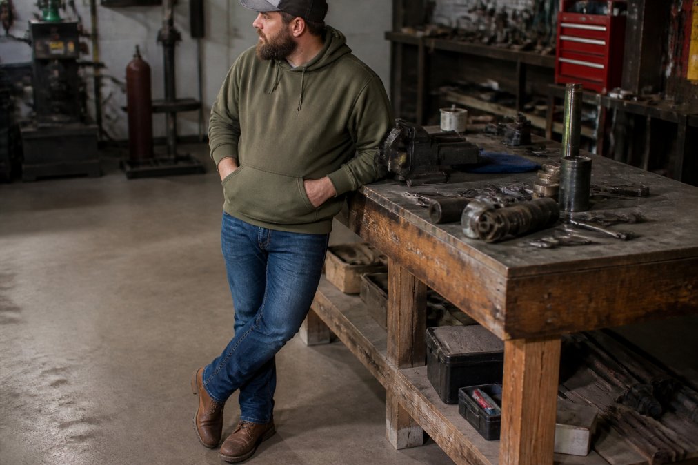 Person wearing Shield Strength Hoodie with jeans and boots in casual setting, demonstrating how the heavy-blend hoodie works with everyday wear