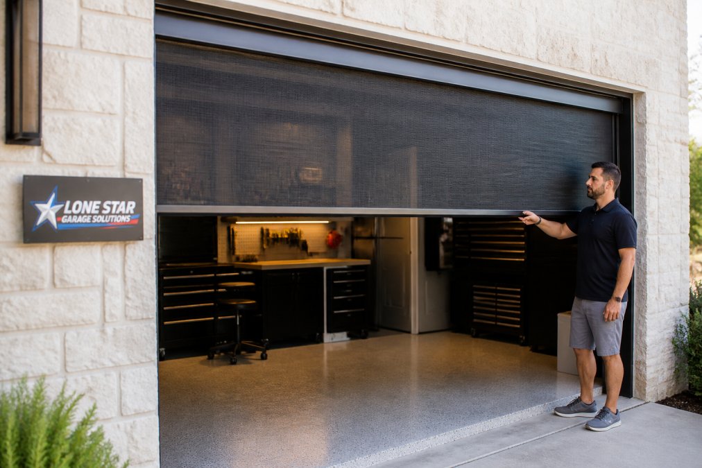 A homeowner in a Central Texas garage with a retractable Lifestyle garage screen partially deployed, showing a clean track system and mesh panel with a workbench and storage visible inside