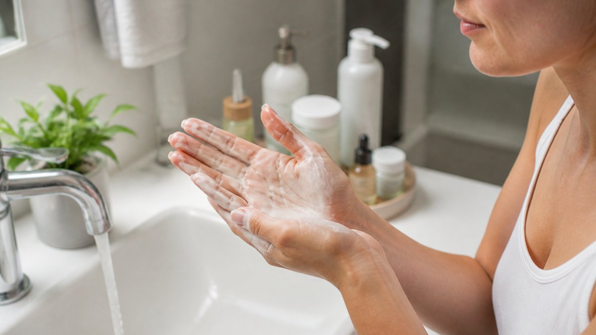 Person with sensitive skin gently lathering cream gentle cleansers in their hands under lukewarm water