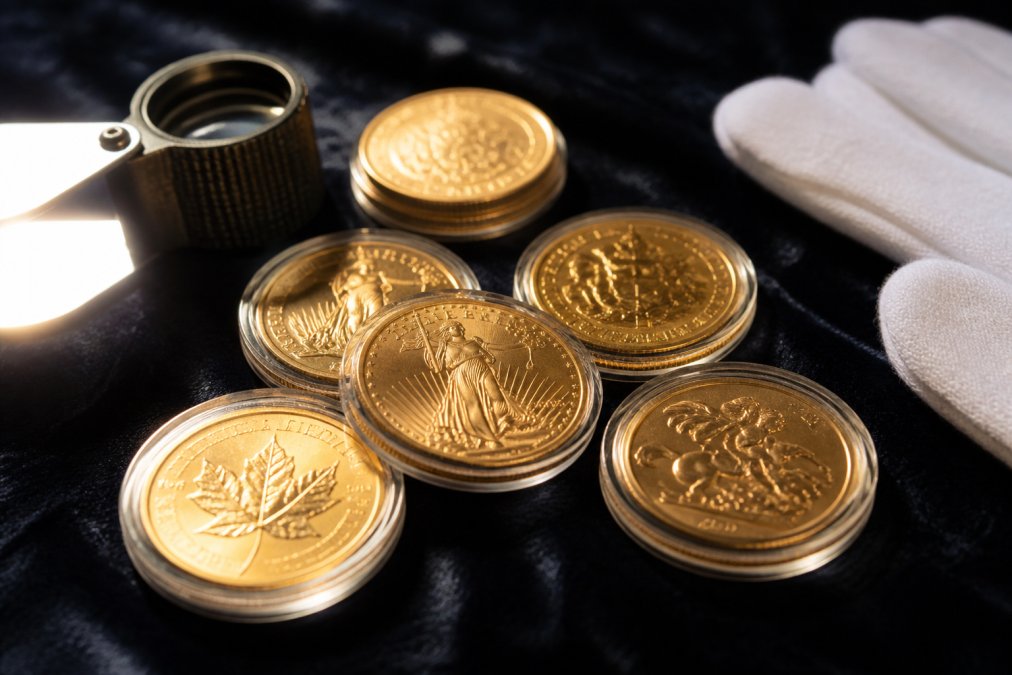 Gold coins arranged on velvet beside a jeweler's loupe and white cotton gloves under warm natural light