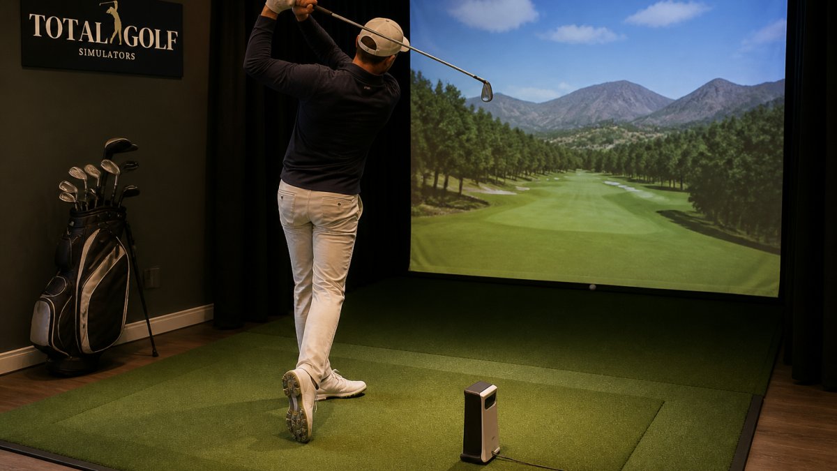Golfer mid-swing in a home simulator bay with a projected virtual course on the screen