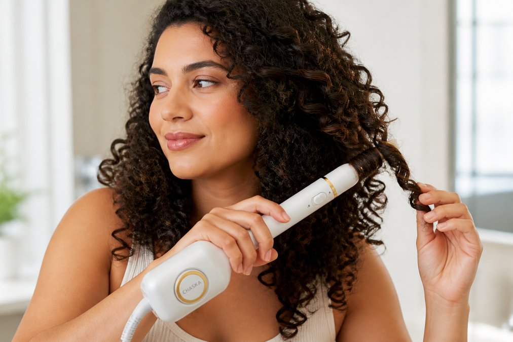 Woman with thick, curly hair using a multi-function styling tool to create defined curls, showing the styling technique and resulting curl definition in natural lighting