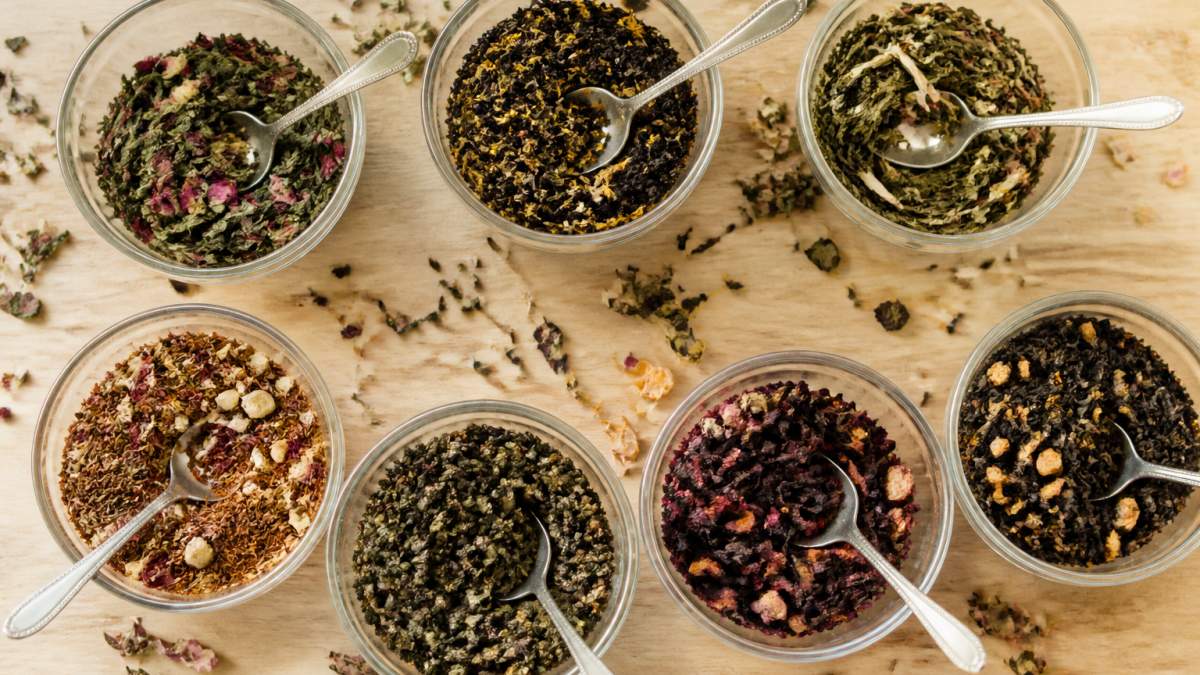 Infographic chart comparing seven loose-leaf tea blends for energy levels in small glass bowls on a wooden table